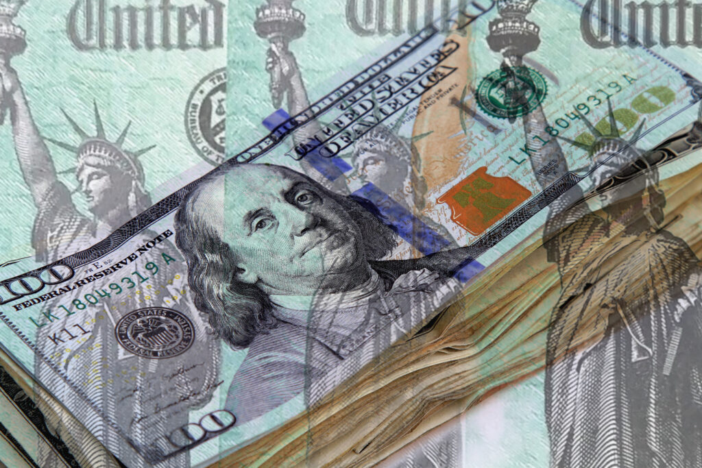 Row of Federal treasury checks over background of a stack of US currency.
