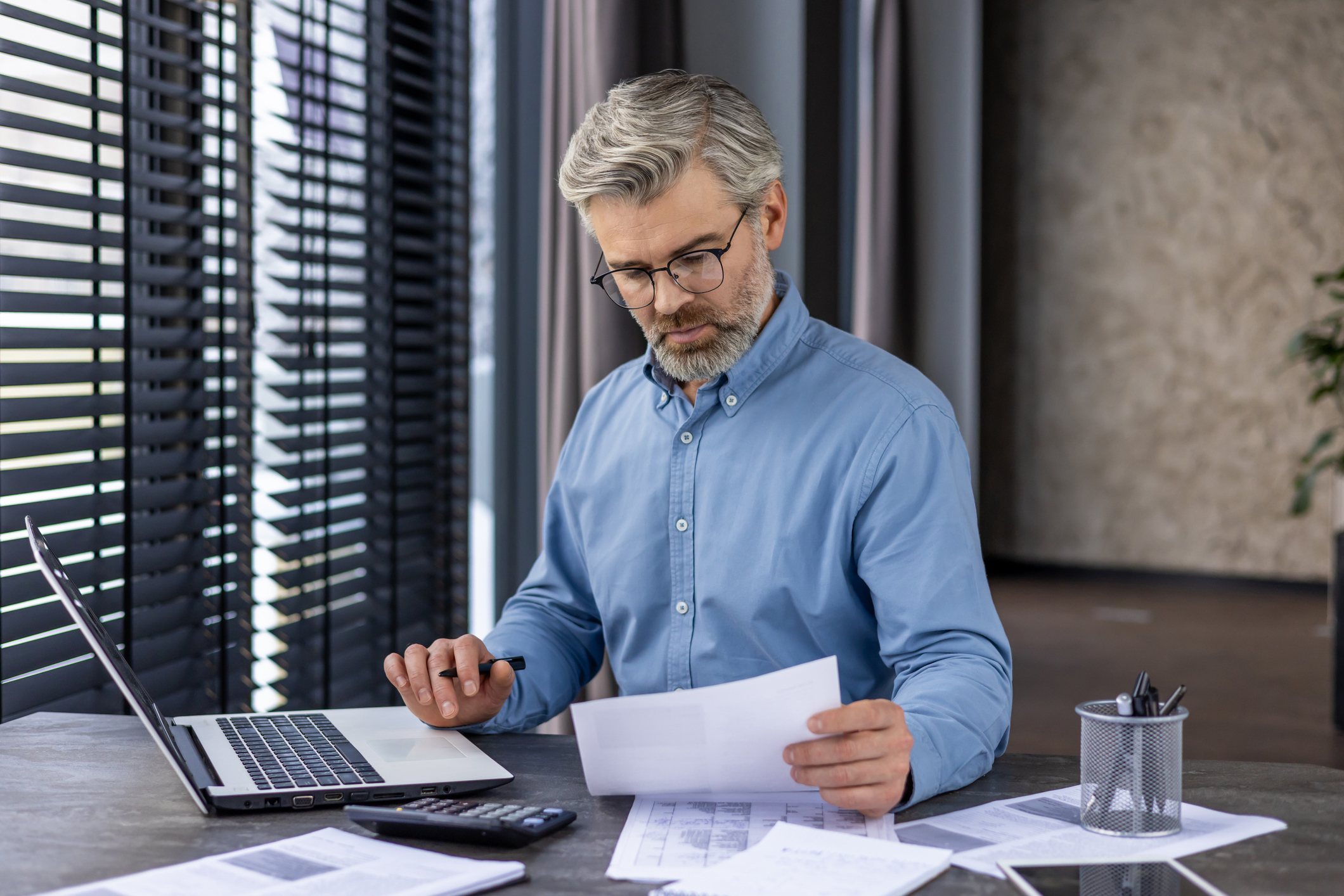 Senior gray-haired man thinking and serious about paper work and taxes.